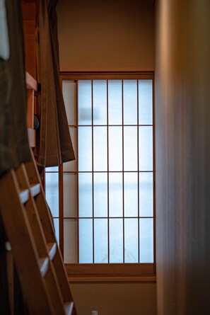 A traditional Japanese room with tatami flooring, a shoji screen, and a wooden ladder. - Miyagawacho Hanakanzashi- Hostel (Kyoto)
