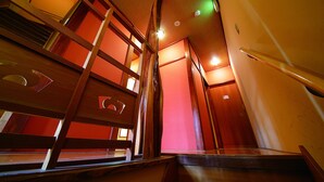 A staircase with wooden railings and a red wall in the background. - Miyagawacho Hanakanzashi- Hostel (Kyoto)