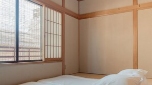 A room with a bed, a window with wooden frames, and a view of a fence outside. - Miyagawacho Hanakanzashi- Hostel (Kyoto)
