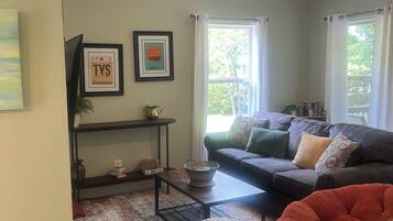 A living room with a sofa, ottoman, and a ceiling fan.