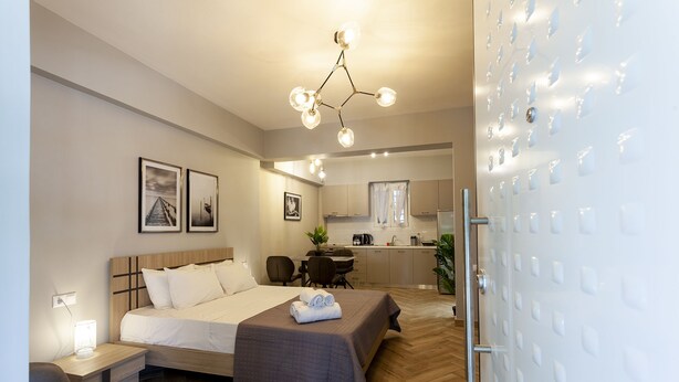 Une chambre d’hôtel moderne équipée d’un grand lit, d’un bureau et d’une kitchenette.