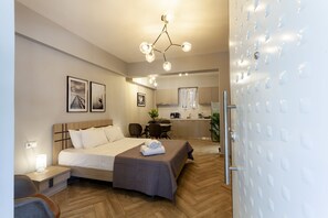 Une chambre d’hôtel moderne équipée d’un grand lit, d’un bureau et d’une kitchenette.