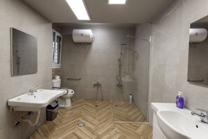 Une salle de bain moderne avec un sol en parquet point de Hongrie, des toilettes, un lavabo, une douche et un miroir.