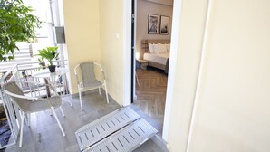 Un balcon avec une table, des chaises et un pot de fleurs.