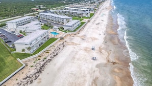 Ett hotell vid stranden med flera byggnader, en swimmingpool och en sandstrand.