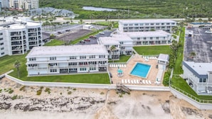 Ett hotell med flera byggnader, en swimmingpool och ett område med strand.