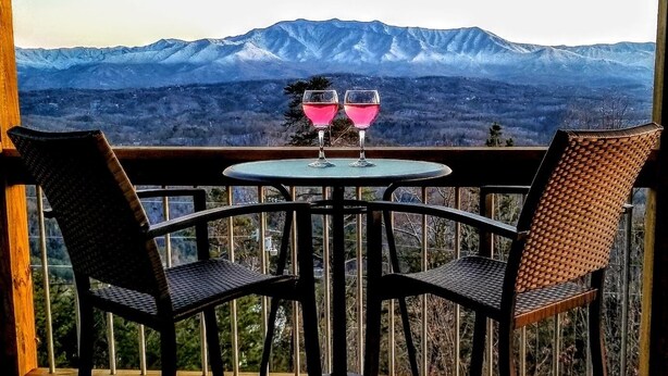 Ein Balkon mit zwei Stühlen und einem Tisch mit Blick auf ein Gebirge.