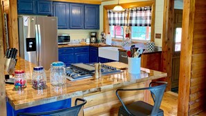 A modern kitchen with a central island, blue cabinets, and a stainless steel refrigerator.