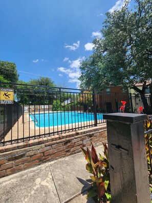 A swimming pool surrounded by a brick wall and a metal fence.