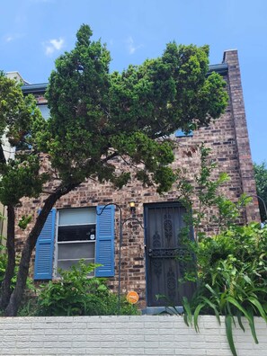 A brick building with blue shutters, a tree in front, and a sign with 'flvint' on it.