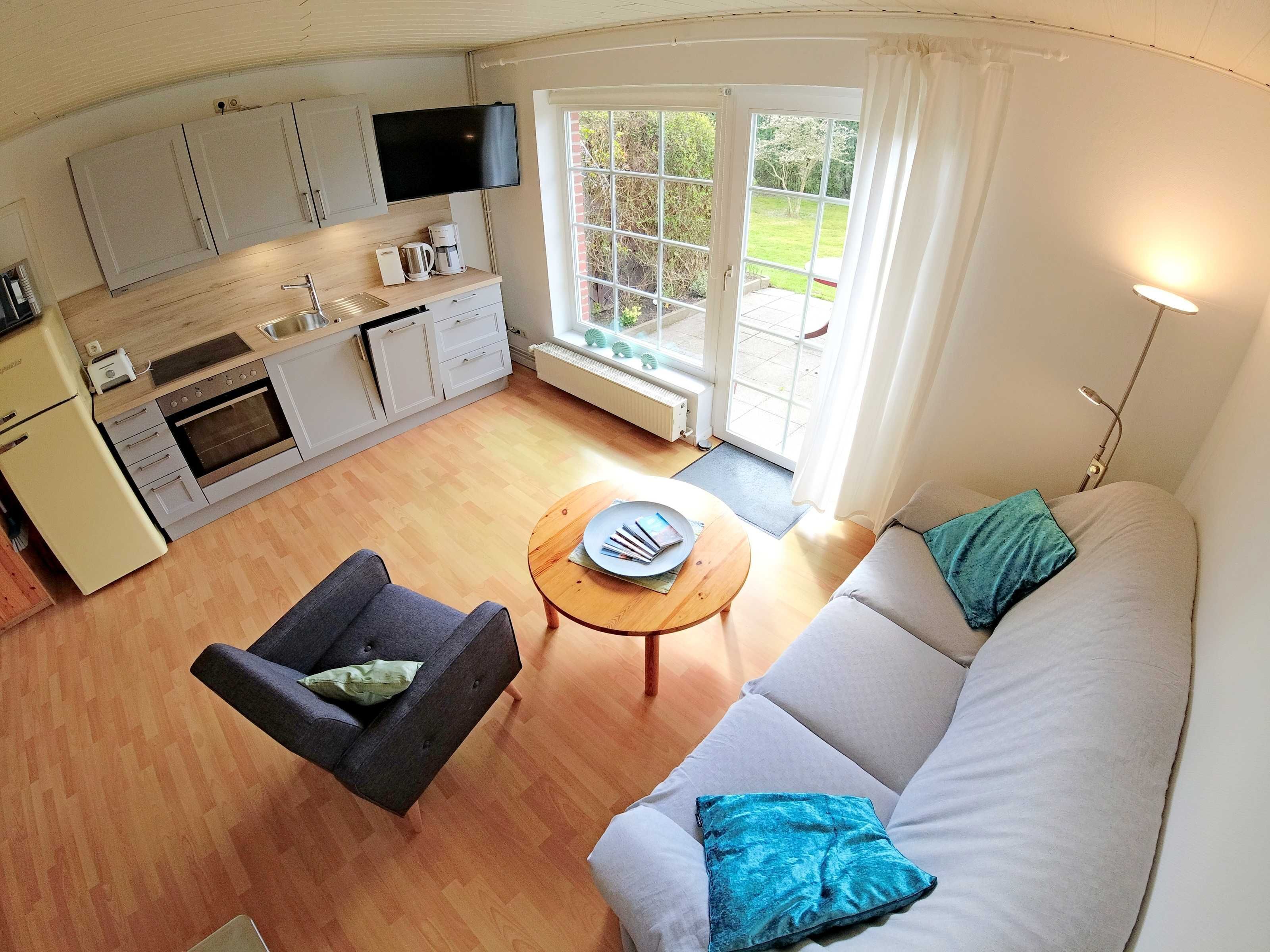 A compact living space with a kitchenette, a sofa, a coffee table, and a television.