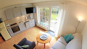 A compact living space with a kitchenette, a sofa, a coffee table, and a television. - Studio Apartment Arnis - Apartments Landhaus Siemens in Kappeln (Kappeln)