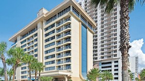A multi-story hotel with balconies, palm trees, and a clear blue sky. - Two Bedroom Luxury Condo, Daytona Beach (1732048) (Daytona Beach)