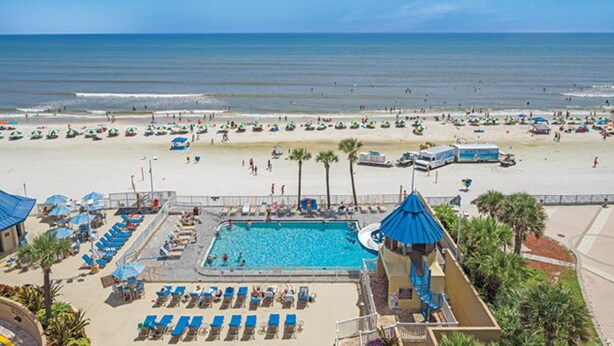 A beach resort with a swimming pool, sun loungers, and beach umbrellas. - Two Bedroom Luxury Condo, Daytona Beach (1732048) (Daytona Beach)