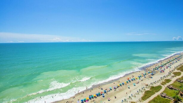 A beach with a long stretch of umbrellas and people. - 2 BALCONIES/DIRECT OCEANFRONT/PET FRIENDLY/CORNER UNIT/ BEST VIEW/RESTAURANT (Myrtle Beach)