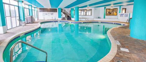 An indoor swimming pool with a closed pool sign, a staircase, and a lifeguard station.