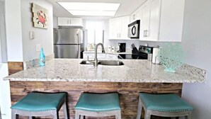Una cocina moderna con una isla central, electrodomésticos de acero inoxidable y una pared de acento de madera.