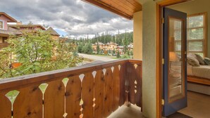 A wooden balcony with a view of a residential area and a building in the background. - Perfectly Located beautiful 4 bedroom townhouse (Sun Peaks)