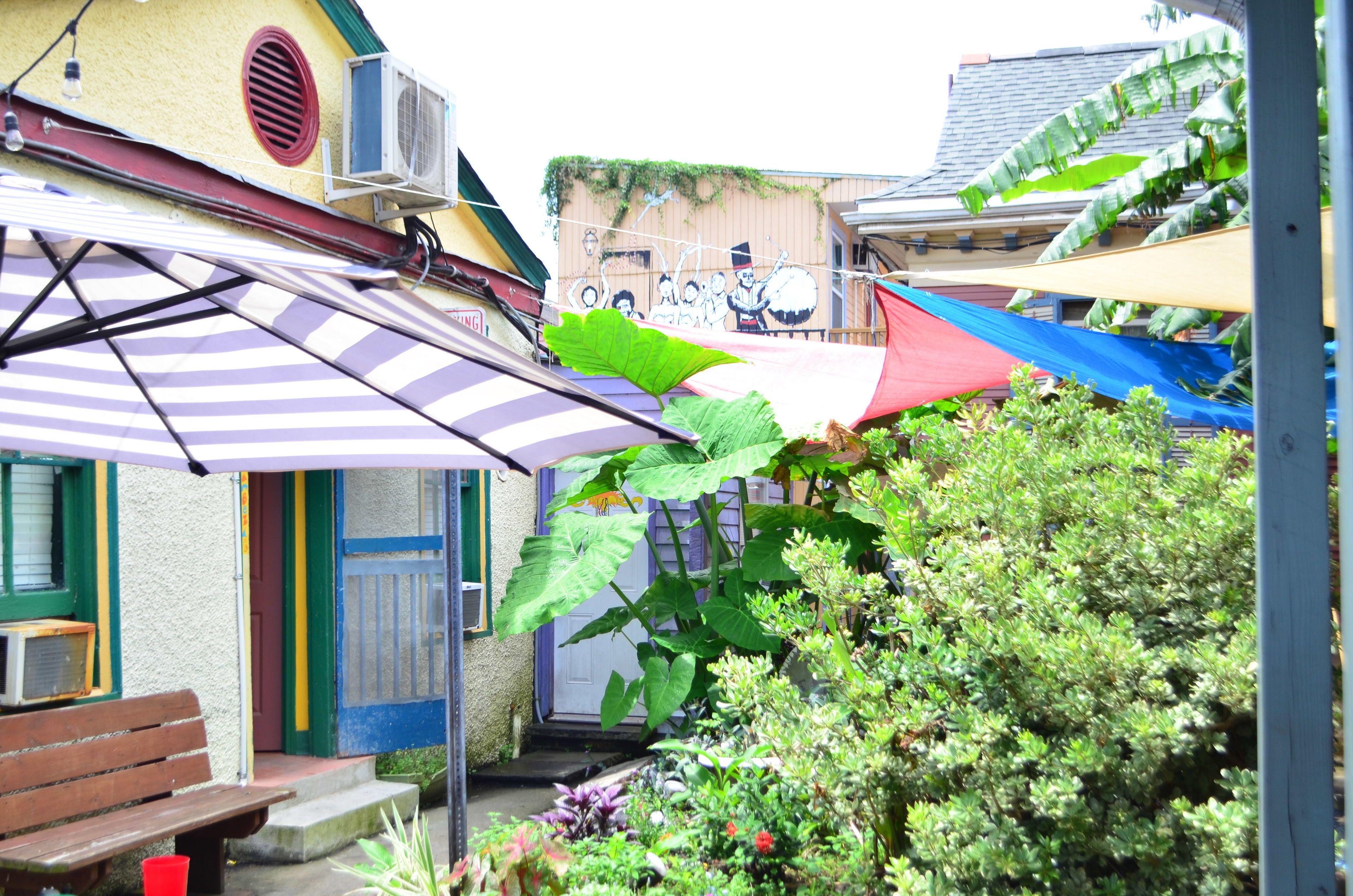 A courtyard with a bench, a door, and a large umbrella.