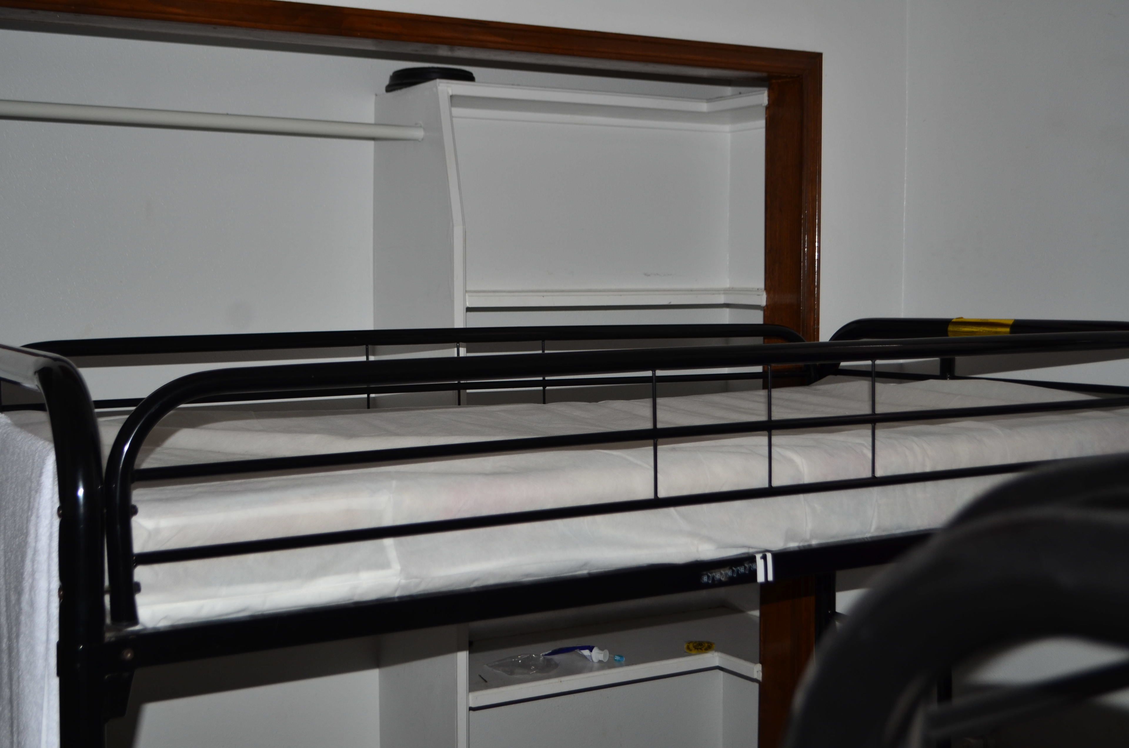 A bunk bed with a white mattress and black metal frame.