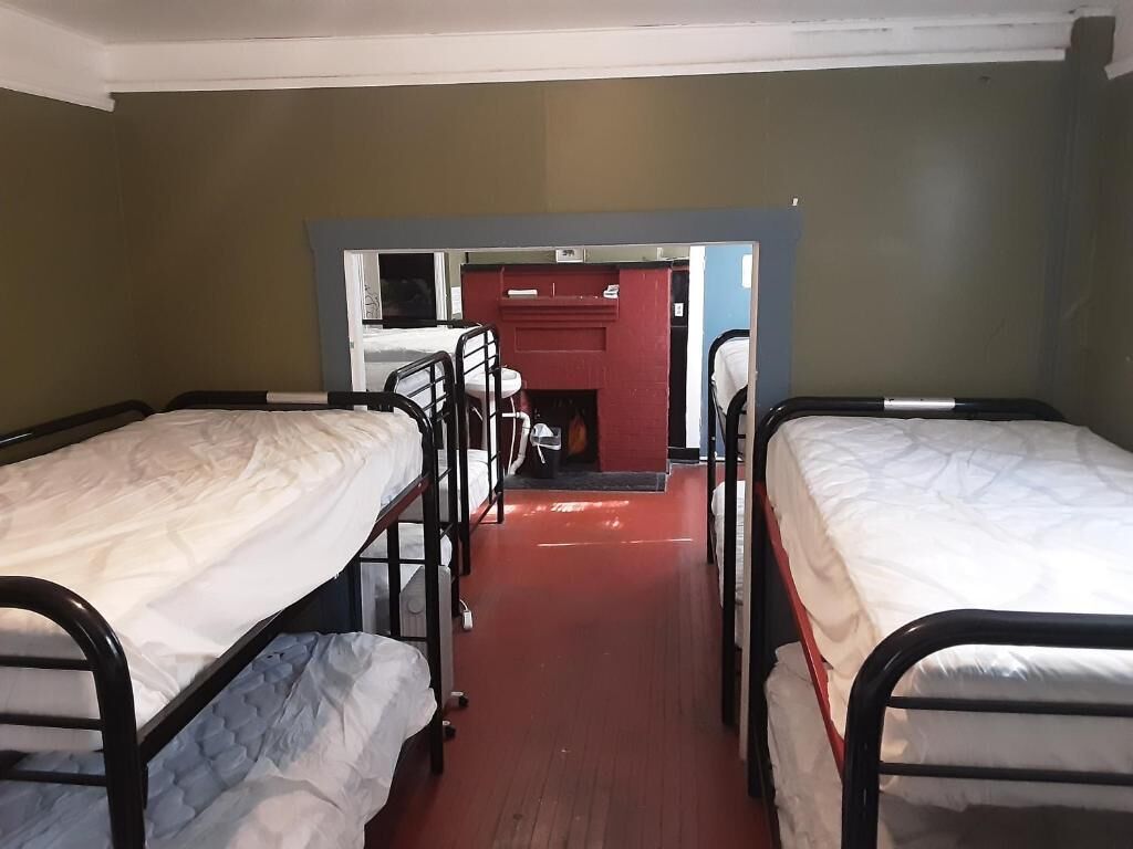 A narrow corridor with bunk beds on either side, leading to a room with a red wall and a sink.