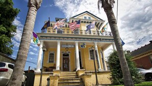 A two-story building with a balcony, flags, and a sign reading "INDIA HOUSE". - India House Backpackers Hostel (New Orleans)
