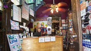 A cozy, eclectic interior with a wooden counter, various signs, and a mural. - India House Backpackers Hostel (New Orleans)