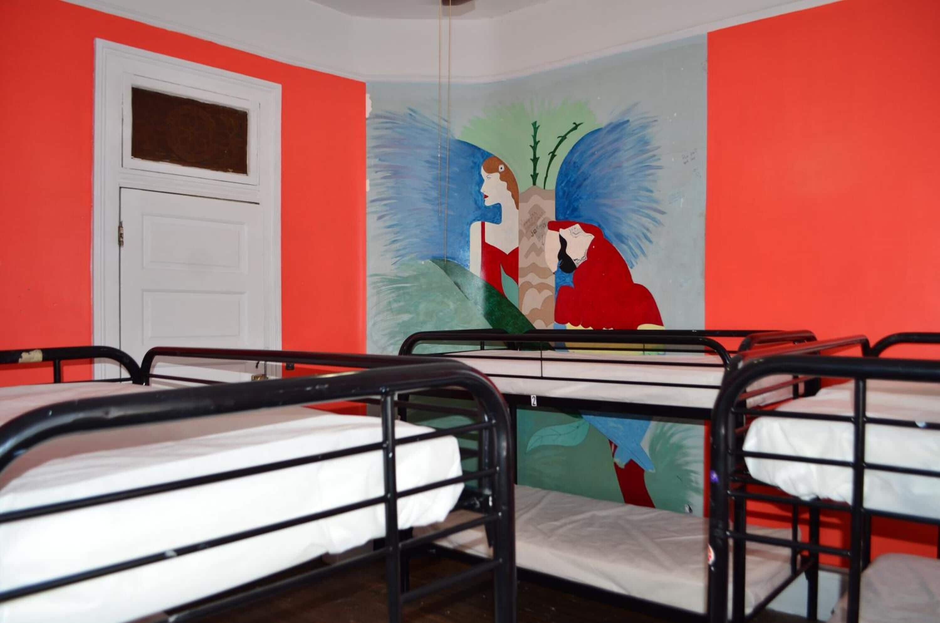 Ein Schlafsaalzimmer mit Etagenbetten, einer weißen Tür und einem Wandgemälde.