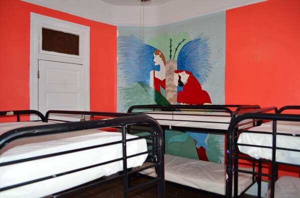 Un dormitorio con literas, una puerta blanca y un mural en la pared.