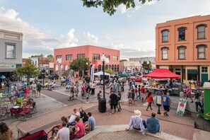 A public square with people sitting and walking around, surrounded by buildings with various storefronts. - 12 Armadillos Main St: 2 Houses/Steps to Dwtn/Sleeps 18/Fun outdoor space! (Brenham)
