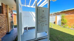 A covered outdoor area with a wooden deck, a white fence, and a garden with various plants. - Yolanda - Burrum Heads- Beachfront - 3BR- Aircon (BURRUM HEADS)