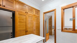 A kitchen with wooden cabinets, a stainless steel refrigerator, and a tiled floor.