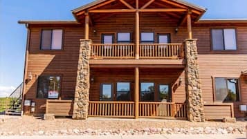 Stunning two-story lodge with a spacious balcony and symmetrical design, featuring a stone foundation and evenly spaced windows.