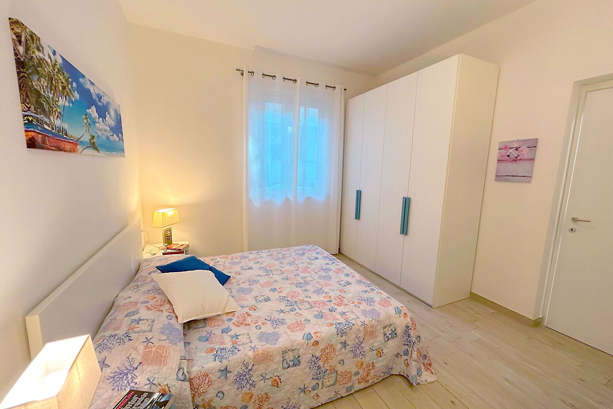 Une chambre à coucher avec un lit, une table de chevet, une lampe, une armoire et une porte.