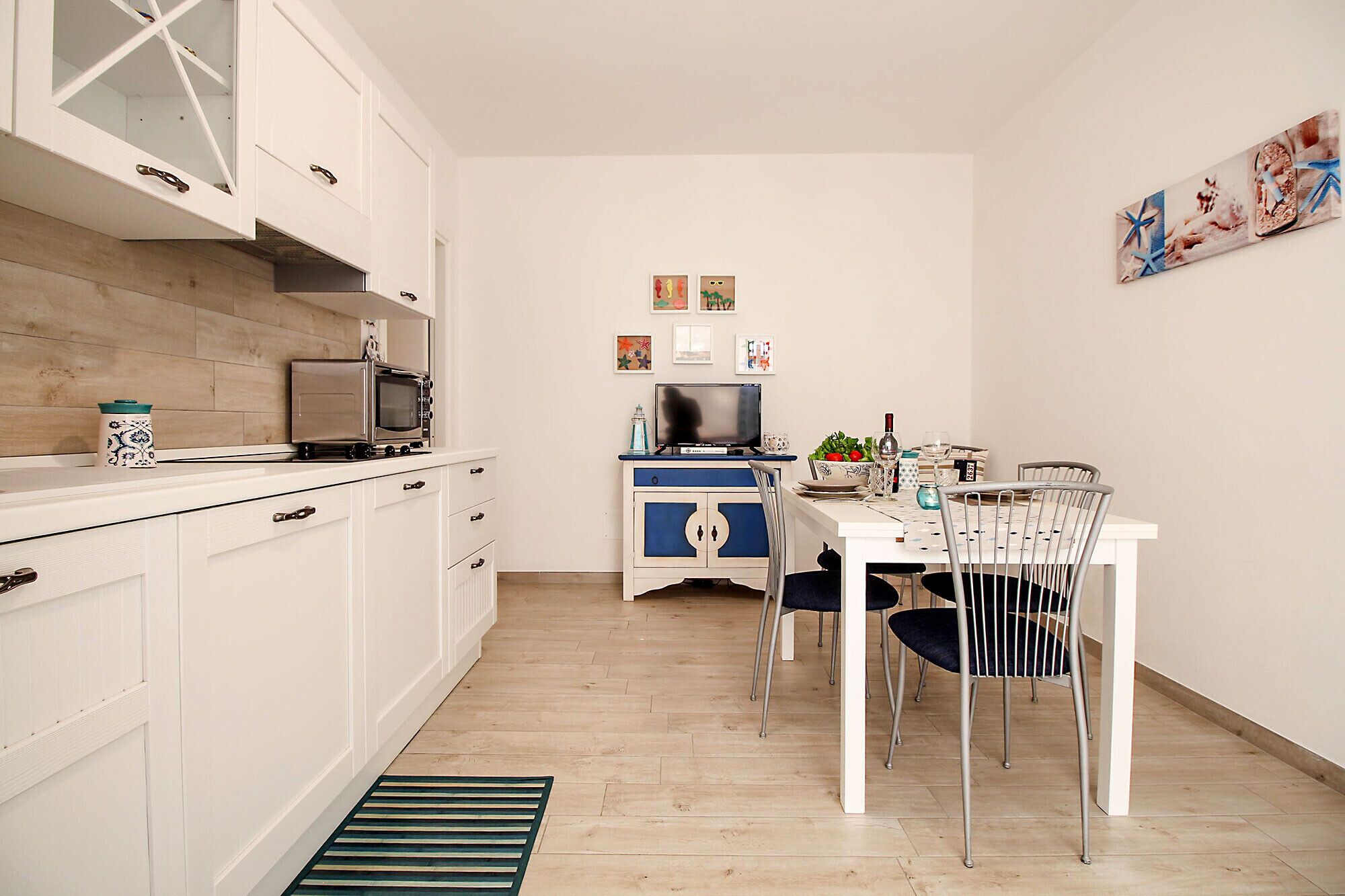 A compact kitchen with white cabinets, a microwave, a stove, and a dining area with a table and chairs.
