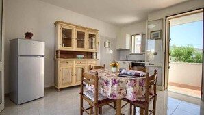 A kitchen with a dining table, wooden cabinets, a refrigerator, and a view of the outdoors. - Dolce Mimi - Two Bedroom House, Sleeps 4 (Pescoluse)