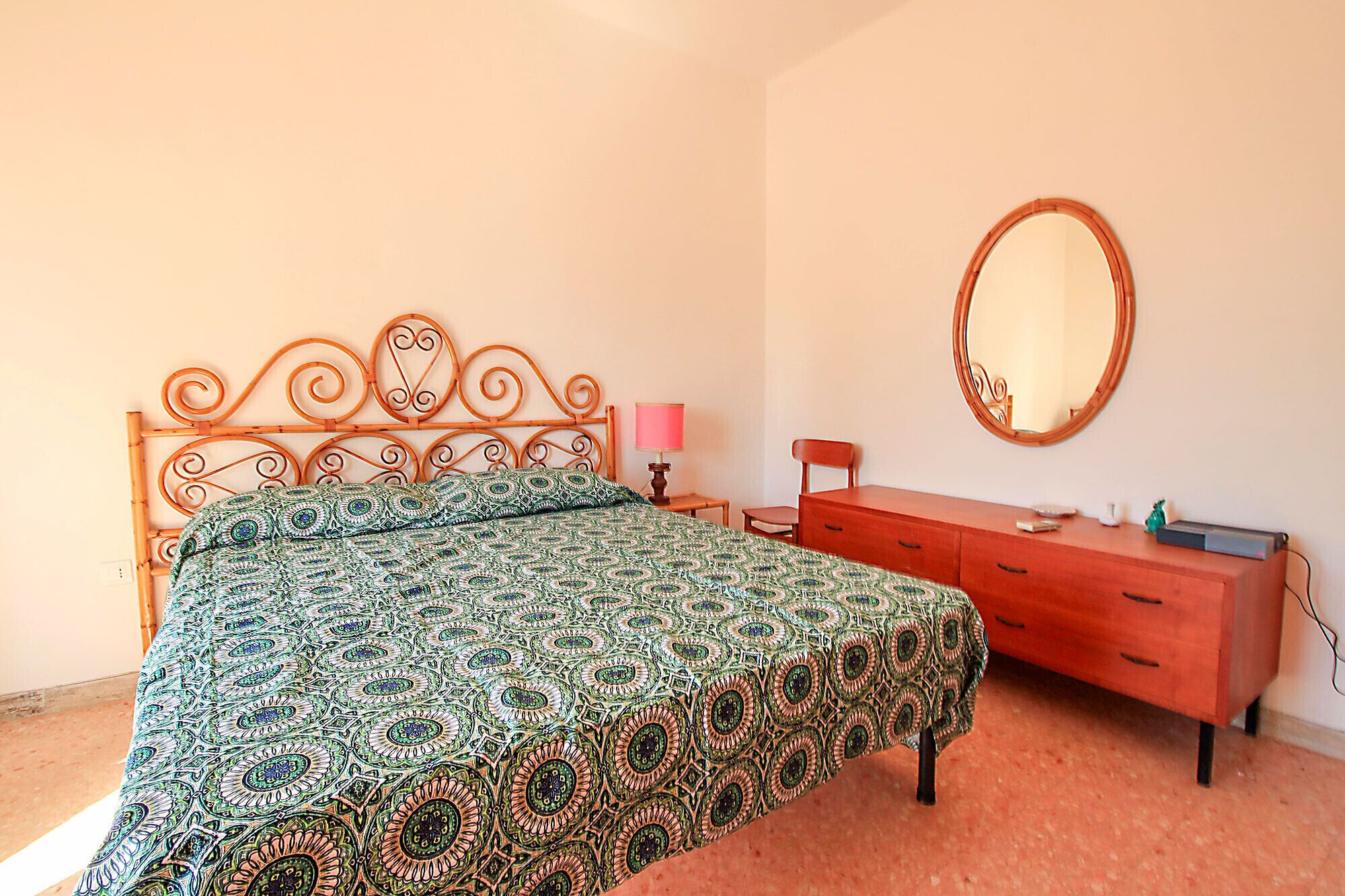 A bedroom with a bed, a dresser, a mirror, and a lamp.
