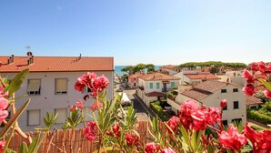 En kystby med terracotta-tag på bygningerne, en klar blå himmel og en gade fyldt med parkerede biler.