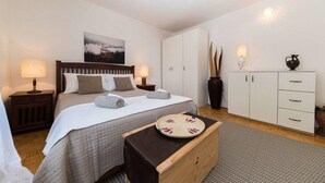 Ein ordentlich eingerichtetes Schlafzimmer mit Bett, Nachttischen, einem Kleiderschrank und einer dekorativen Ablagefläche.