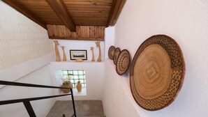 Eine Treppe mit Holzboden, ein kleines Fenster mit Blick und wandhängende gewebte Körbe.