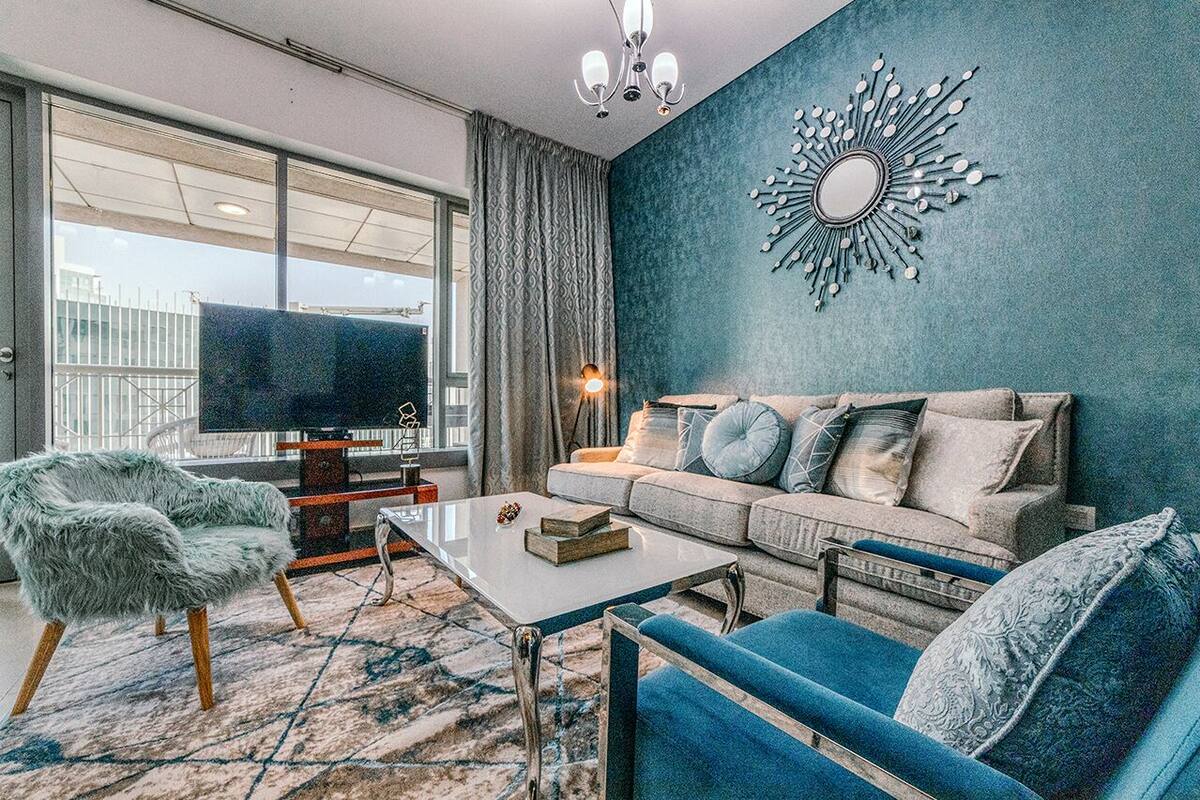 A modern living room with a large window, a sofa set, a coffee table, and a decorative wall piece.