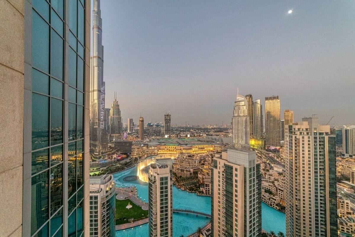 A high-rise building with a modern glass facade, a river running through the city, and other surrounding skyscrapers.