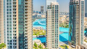 A high-rise hotel with multiple balconies, a swimming pool, and a view of the surrounding cityscape.