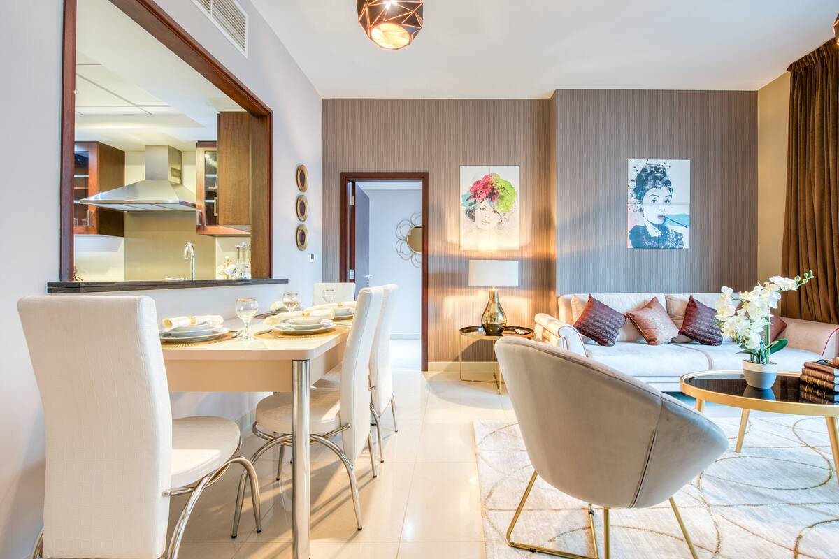 A modern living room with a sofa, coffee table, and dining area with chairs and a table set for a meal.