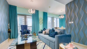 A modern living room with a blue sofa, a glass coffee table, and a blue armchair.