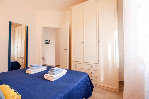 A bedroom with a bed, a wardrobe, and a mirror. - Apartment Timone near the sea (Marina di Grosseto)