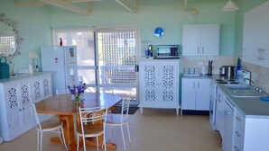 A kitchen with white cabinets, a wooden dining table, and chairs.