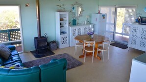 A cozy living room with a sofa, a dining table with chairs, a fireplace, and a kitchen area with a refrigerator.