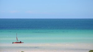 A calm beach with a small sailboat in the water.