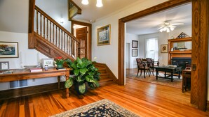Un vaste salon doté d’un escalier en bois, d’un coin repas et d’une cheminée.